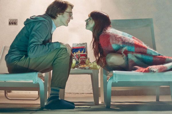 An screenshot of the movie Ruby Sparks, as a man and a woman lean closer to each other next to a pool at night.